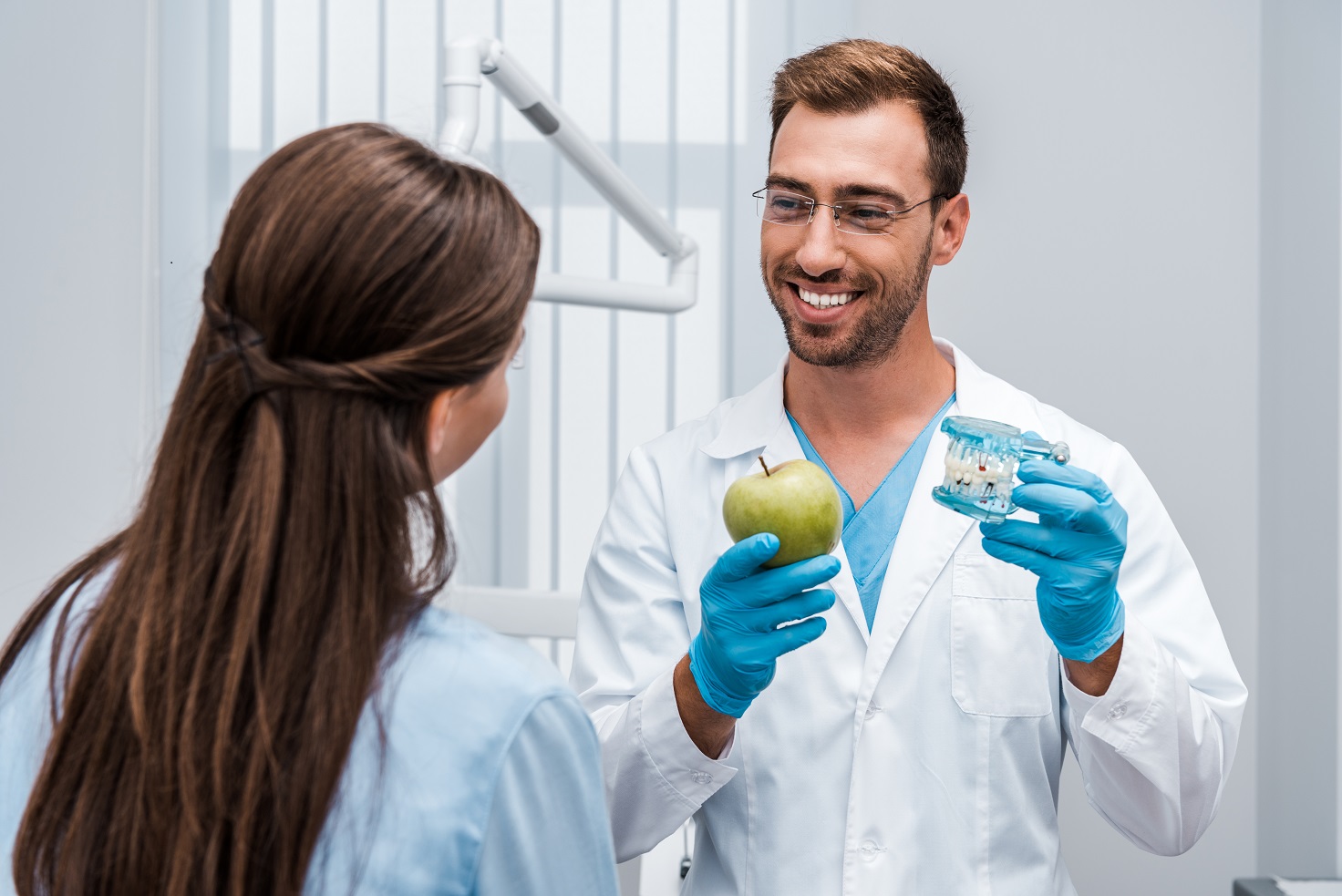 dentist holding tooth model near patient