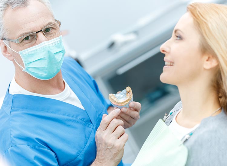 dentist showing patient a mouth model