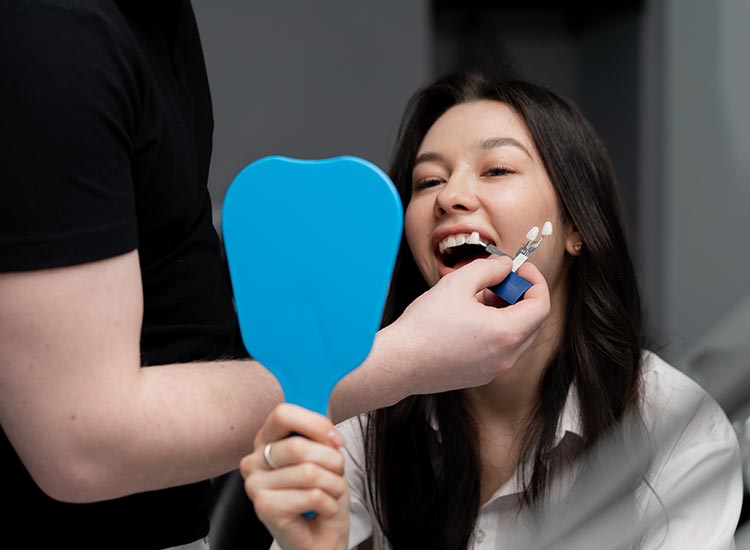 patient smiling with mirror showing new teeth veneers