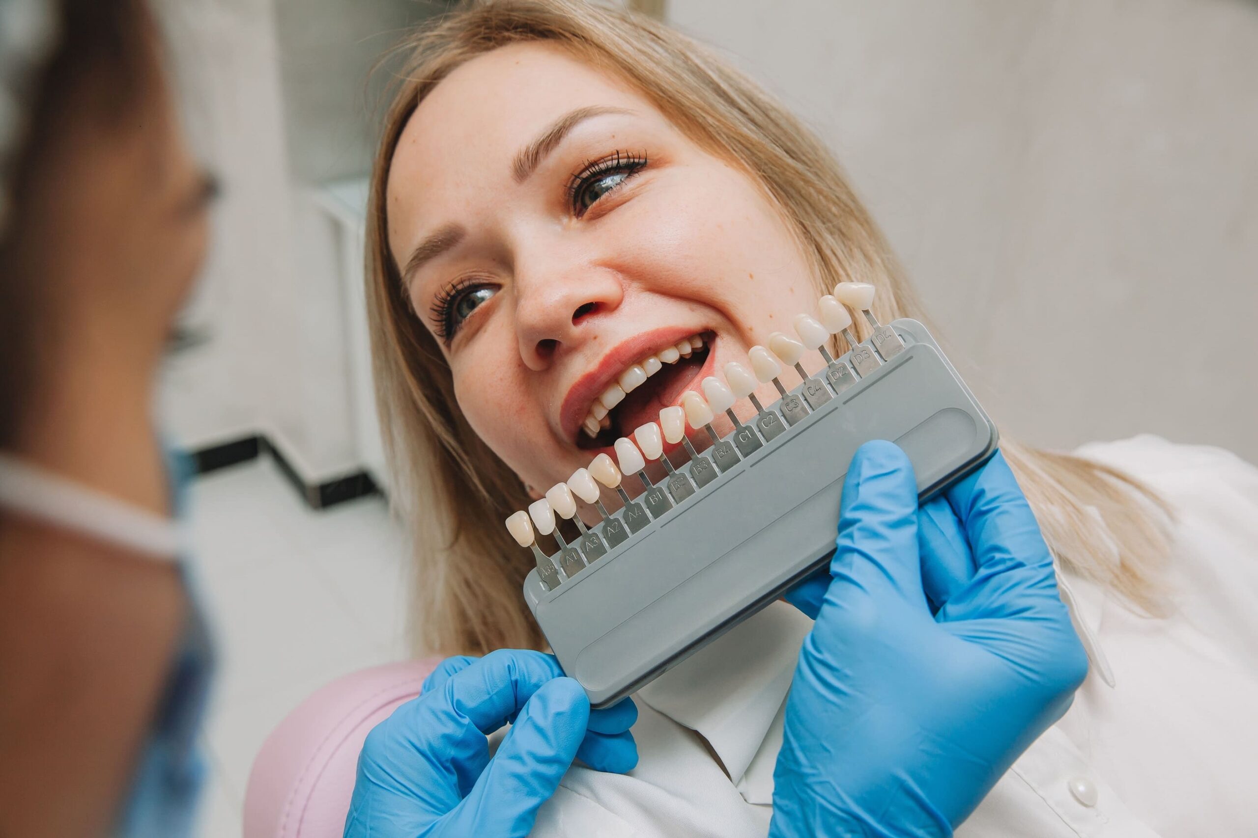 the girl in the dentist office selects the color of veneers