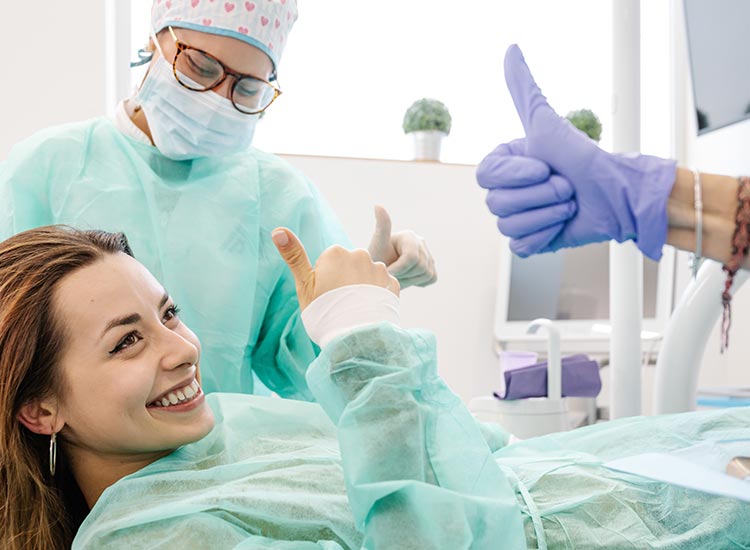 patient providing a thumbs up to dentist